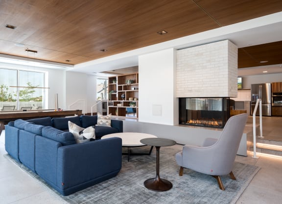 entertainment suite with couch seating and a cozy fireplace. Pool table behind the couch.