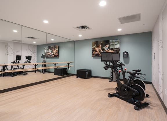 Spin or yoga studio with two workout cycles in right corner and large wall of mirrors on the left.