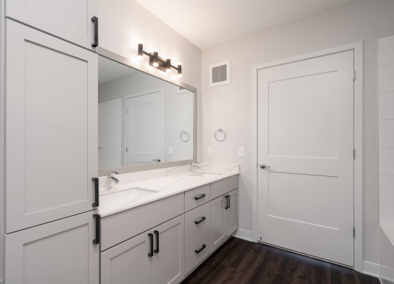 large white double vanity with large mirror and tall storage cabinet on the right