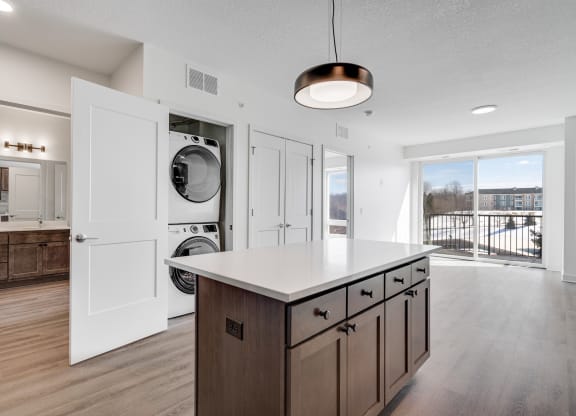 Kitchen island counter space with hidden stacked washer and dryer at The Rowan in Eagan Minnesota