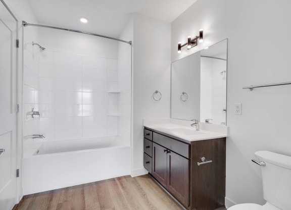 Bathroom with dark brown vanity and linen cabinet for storage and large mirror at The Rowan in Eagan Minnesota