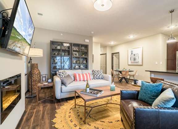 A modern living room with a fireplace and a large TV mounted on the wall.