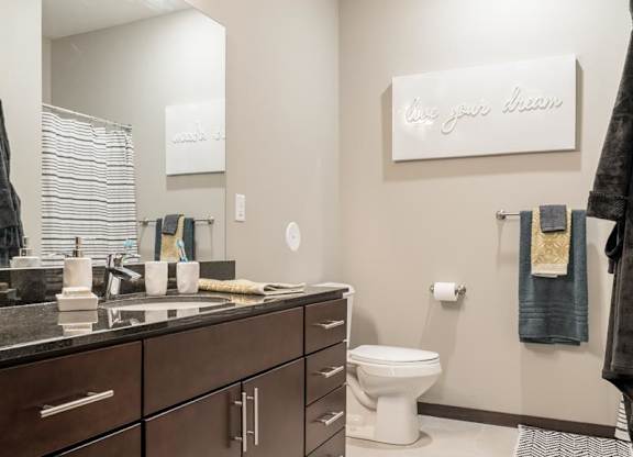 A bathroom with a toilet, sink, and mirror.