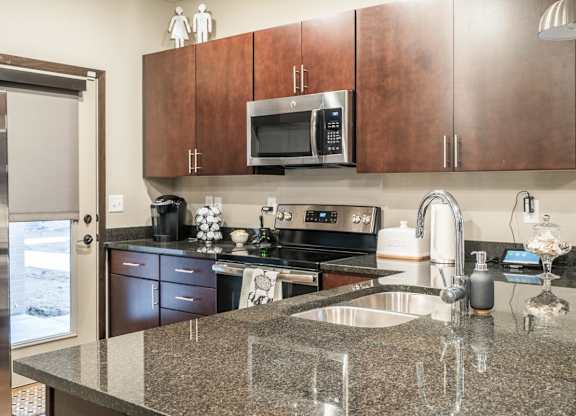 A kitchen with cherry cabinets, granite counter top and stainless steel appliances.