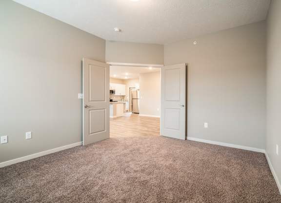 A room with a carpeted floor and two doors.