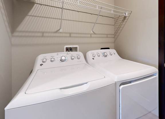 A white washer and dryer with a shelf above them in small laundry room