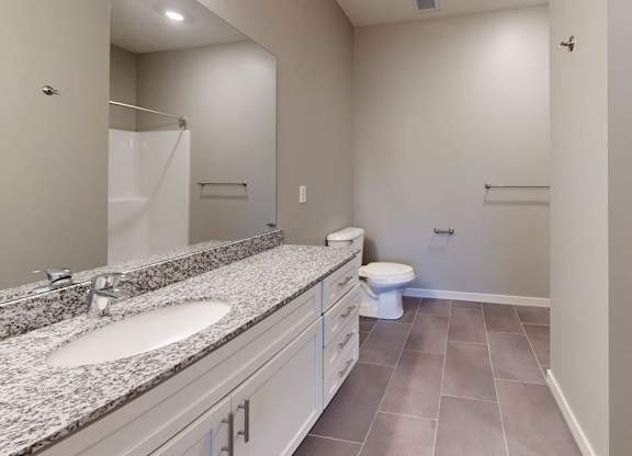 A bathroom with a toilet, sink, and shower, plus an attached closet.