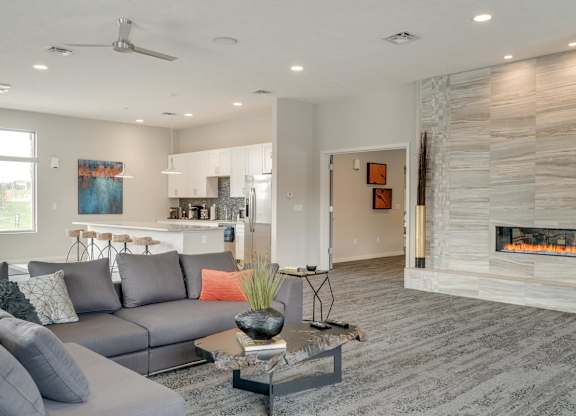 A modern clubhouse great room with a grey sofa and a fireplace.