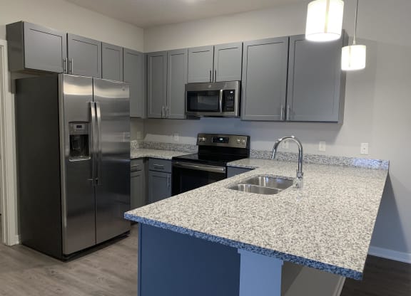 Kitchen with slate gray cabinets and matching stainless steel appliances at The Villas at Mahoney Park