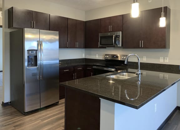 Kitchen with dark brown cabinets and matching stainless steel appliances in a the grand canyon floorplan at the villas at mahoney park