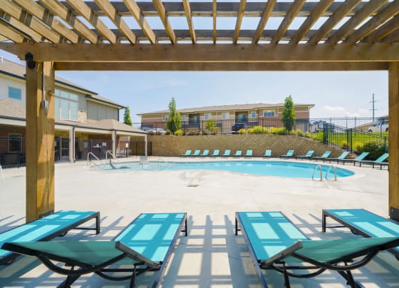 lounge chairs under a pergola overlooking a resort-style pool