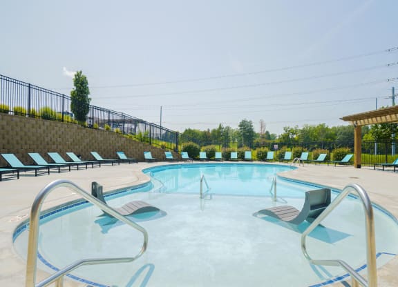 a resort-style pool with two lounge chairs in the  shallow wading are of the water