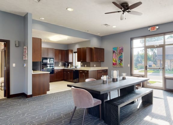 a dining area in the clubhouse with a table and chairs and a kitchen in the background
