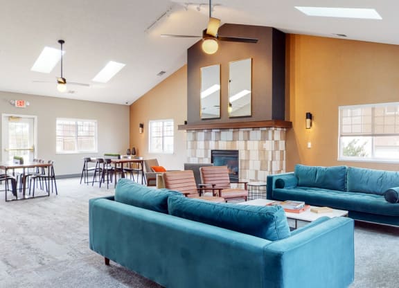 Spacious clubhouse with vaulted ceiling, natural light, fireplace and sitting areas at the Northbrook Apartments