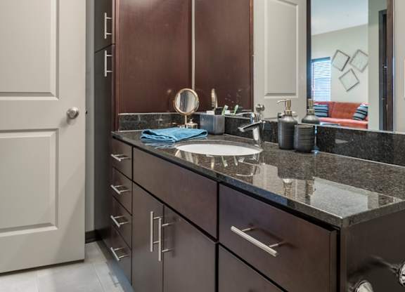 A bathroom with a sink, mirror, and cabinets.