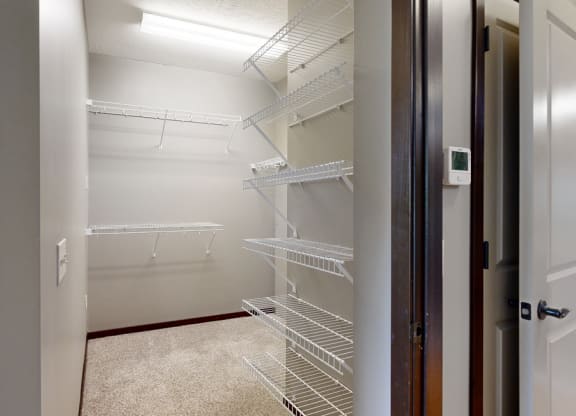 a walk-in closet in the bedroom with lots of shelves