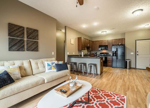 A modern living room with a kitchen in the background.