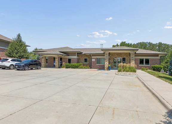 Villas of Omaha at Butler Ridge community building exterior with brick and stone finishes, landscaped entrance, and parking area.