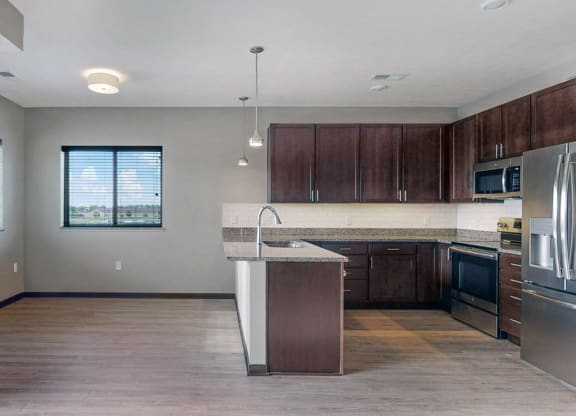 The 2 bedroom Snowdrop with den floor plan at WH Flats features an open eat-in kitchen area with granite countertops and large peninsula.