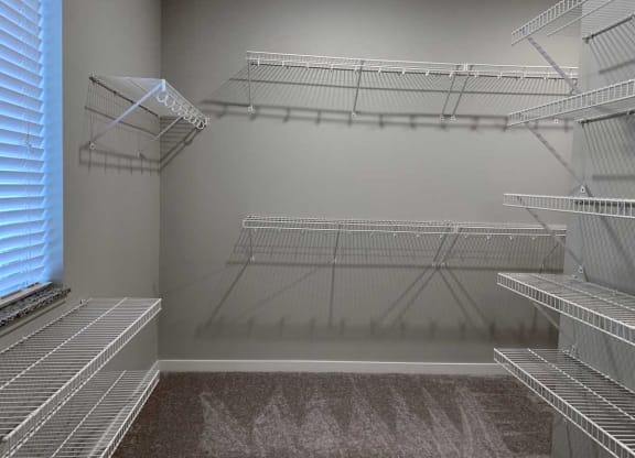 the walk in closet of a home with empty shelves