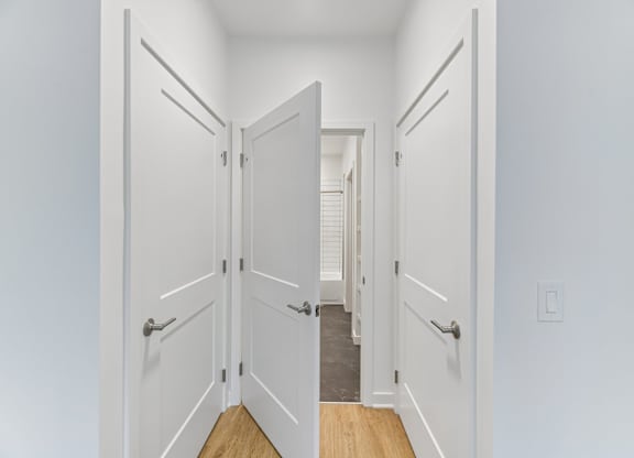A hallway with white doors and a wooden floor.