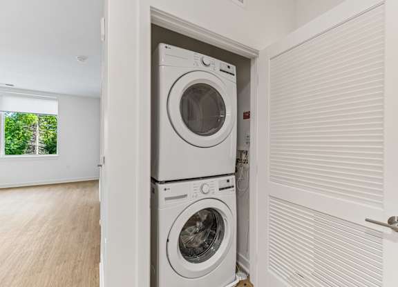 A white washing machine is in a white laundry room.