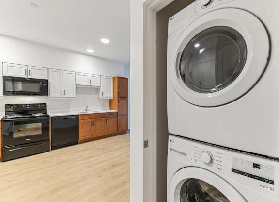 A white washing machine is stacked on top of a white dryer in a kitchen.