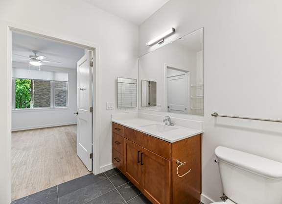 A white bathroom with a wooden vanity and a white tub.