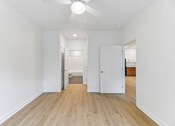 A room with a ceiling fan and wooden flooring.