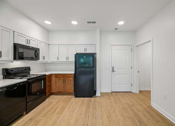 A kitchen with black appliances and wooden floors.