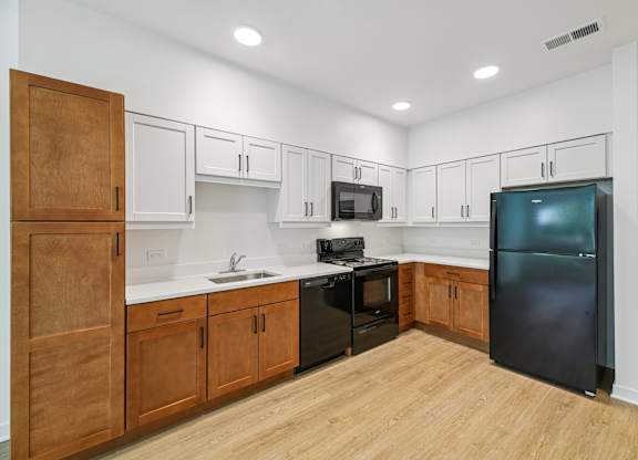 A kitchen with wooden cabinets and a black refrigerator.