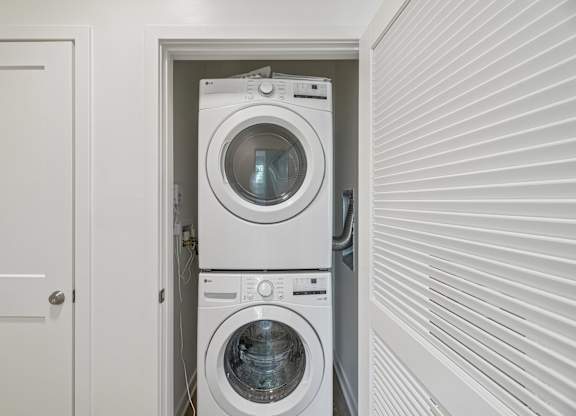 A white door is open to a small laundry room with a washer and dryer.