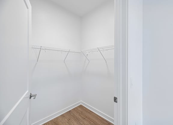 A white closet with a wooden floor and a white door.