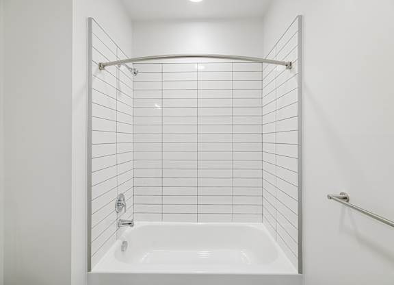 A white bathroom with a white tub and white tiles.