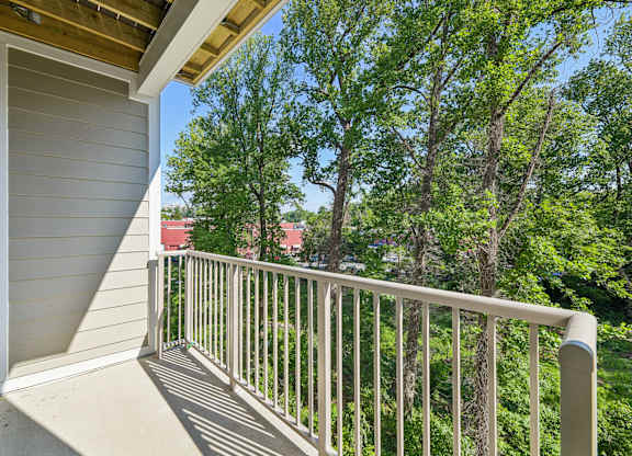 A balcony with a white railing overlooks a green tree.