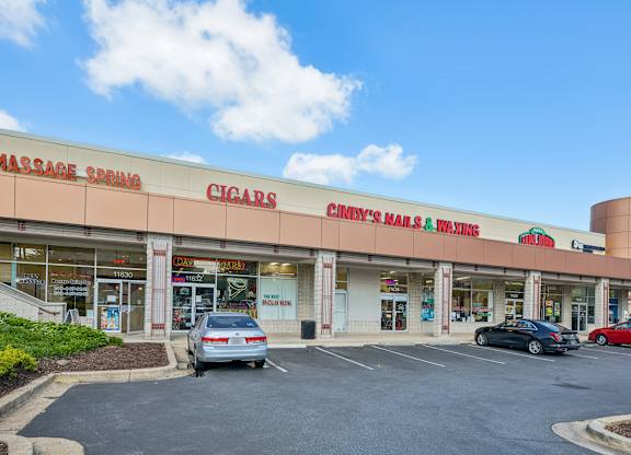 A cigar store with cars parked in front.