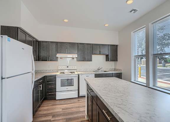 A kitchen with a white refrigerator and black cabinets.