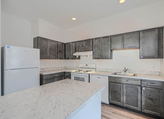 A kitchen with a refrigerator, sink, and cabinets.