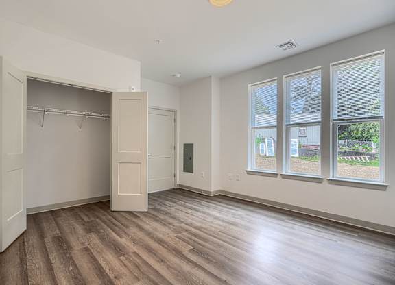 A room with a large closet and a window overlooking a street.