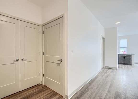 A room with a white wall and a wooden floor with a white door.