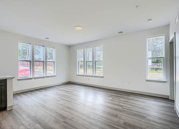 A large empty room with wooden floors and windows.