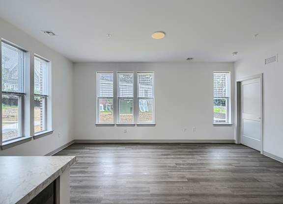 A large empty room with a kitchen island and windows.