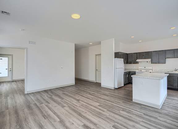 A kitchen with a white fridge and wooden floors.