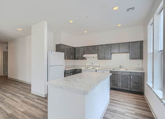 A kitchen with a marble countertop and wooden floors.