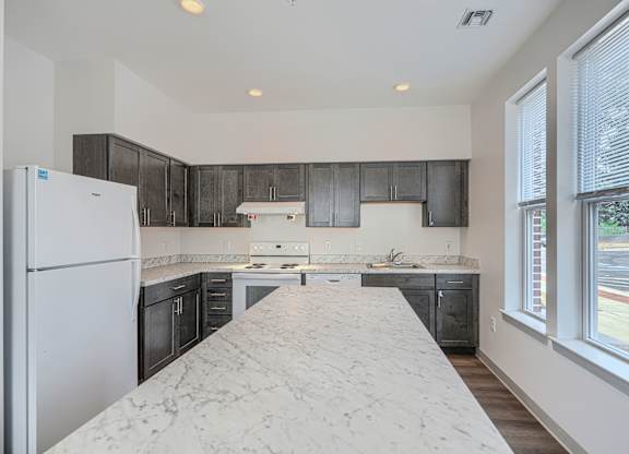 A kitchen with a marble countertop and black cabinets.