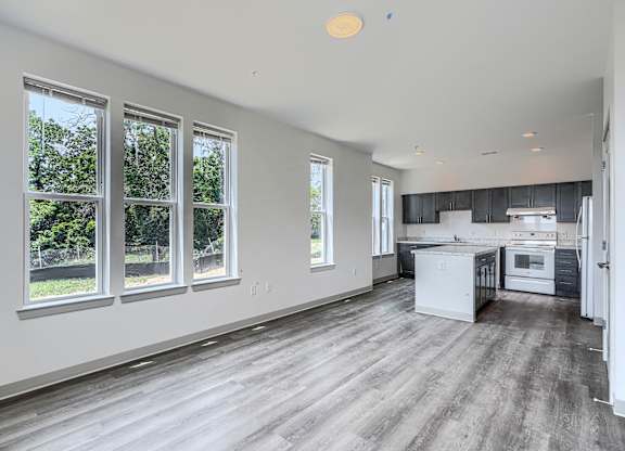 A spacious kitchen and living room with hardwood floors and large windows.
