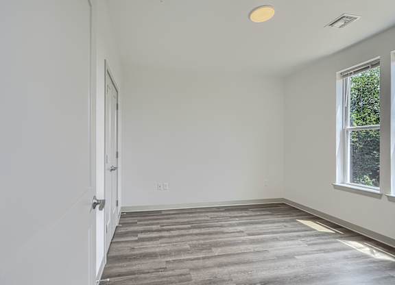 A room with a wooden floor and a window on the right side.