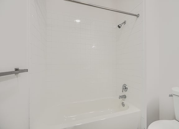 A white bathroom with a tub and toilet.