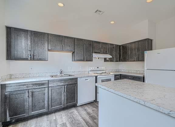 A kitchen with dark wood cabinets and white appliances.