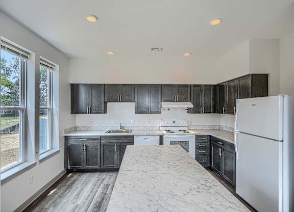 A kitchen with black cabinets and a white refrigerator.